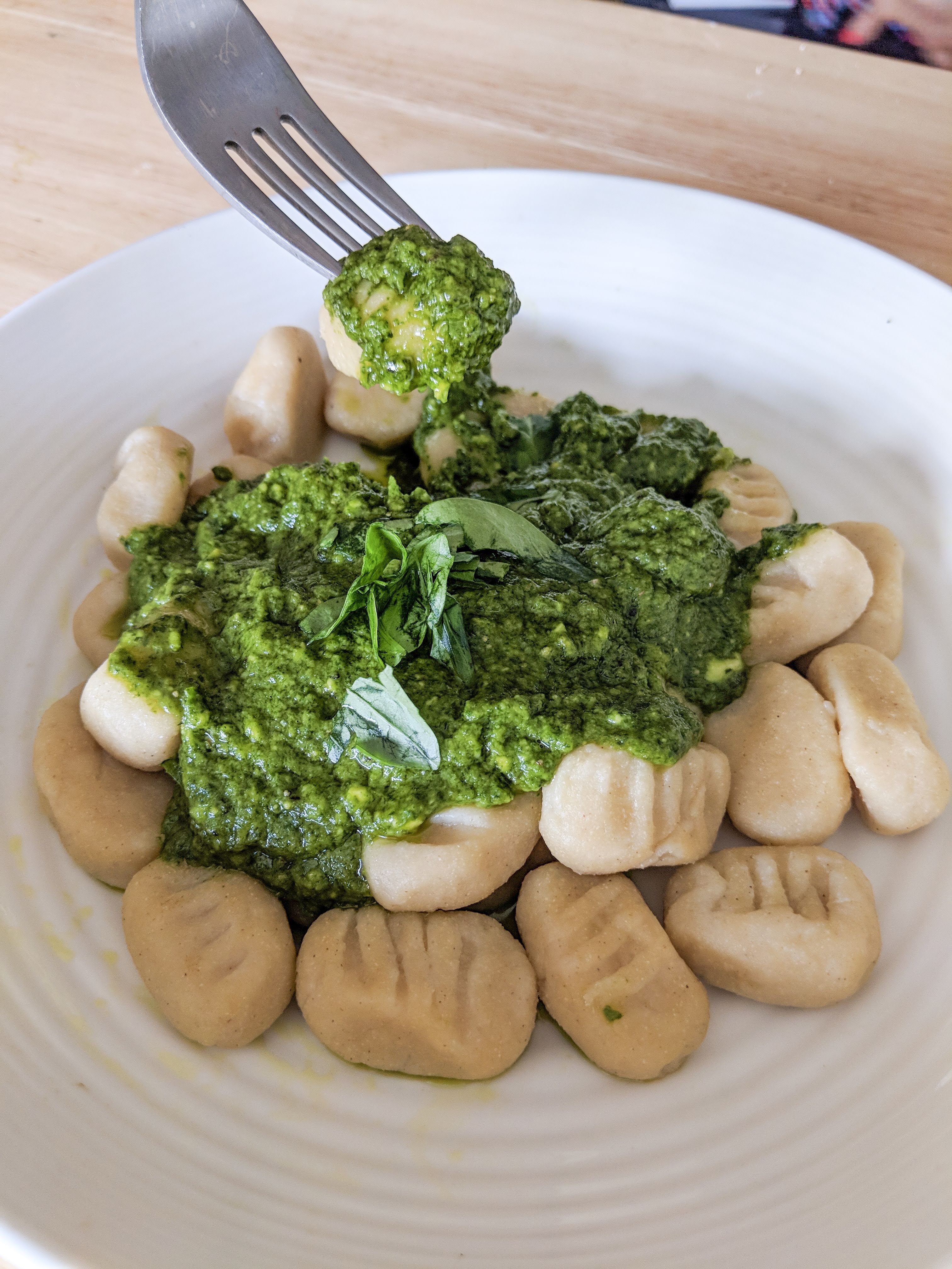 A plate full of cauliflower gnocchi with avocado spinach pesto on top