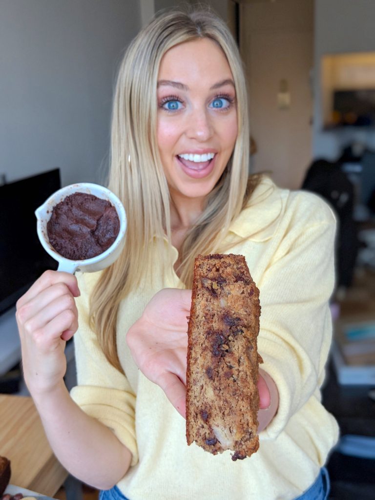 Skyler Bouchard holding a slice of  dark chocolate hazelnut banana bread with banana slices and hazelnut spread