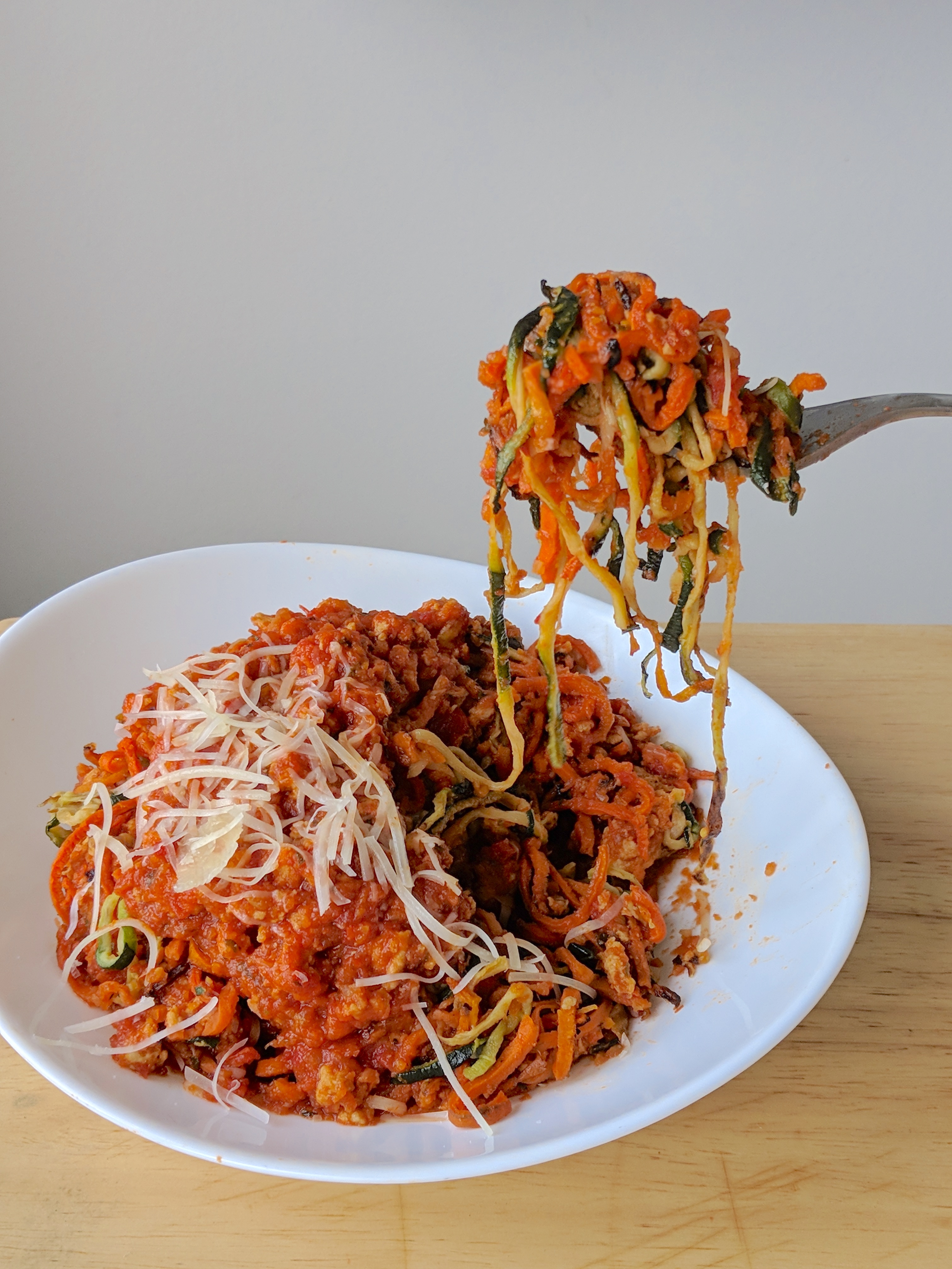 carrot and zucchini noodles in a chicken bolognese sauce with parmesan cheese