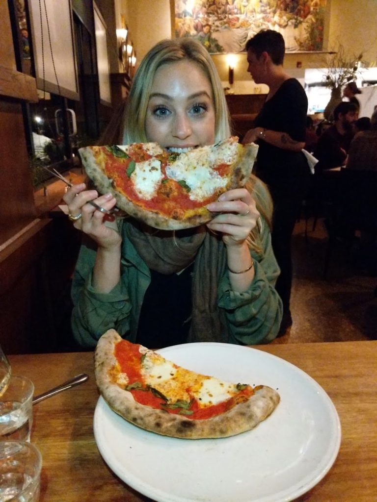 A girl smiling with pizza at Nostrana Portland Oregon
