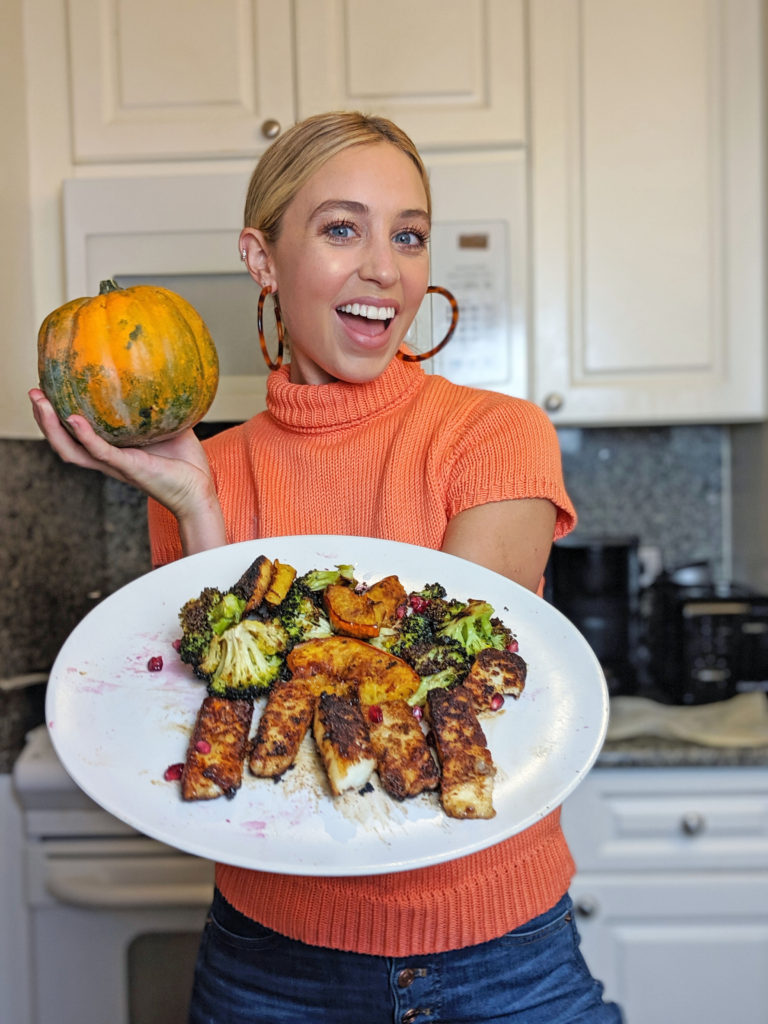 Skyler Bouchard with a plate of seared golden brown pumpkin spice halloumi with broccoli and acorn squash and pomegranate