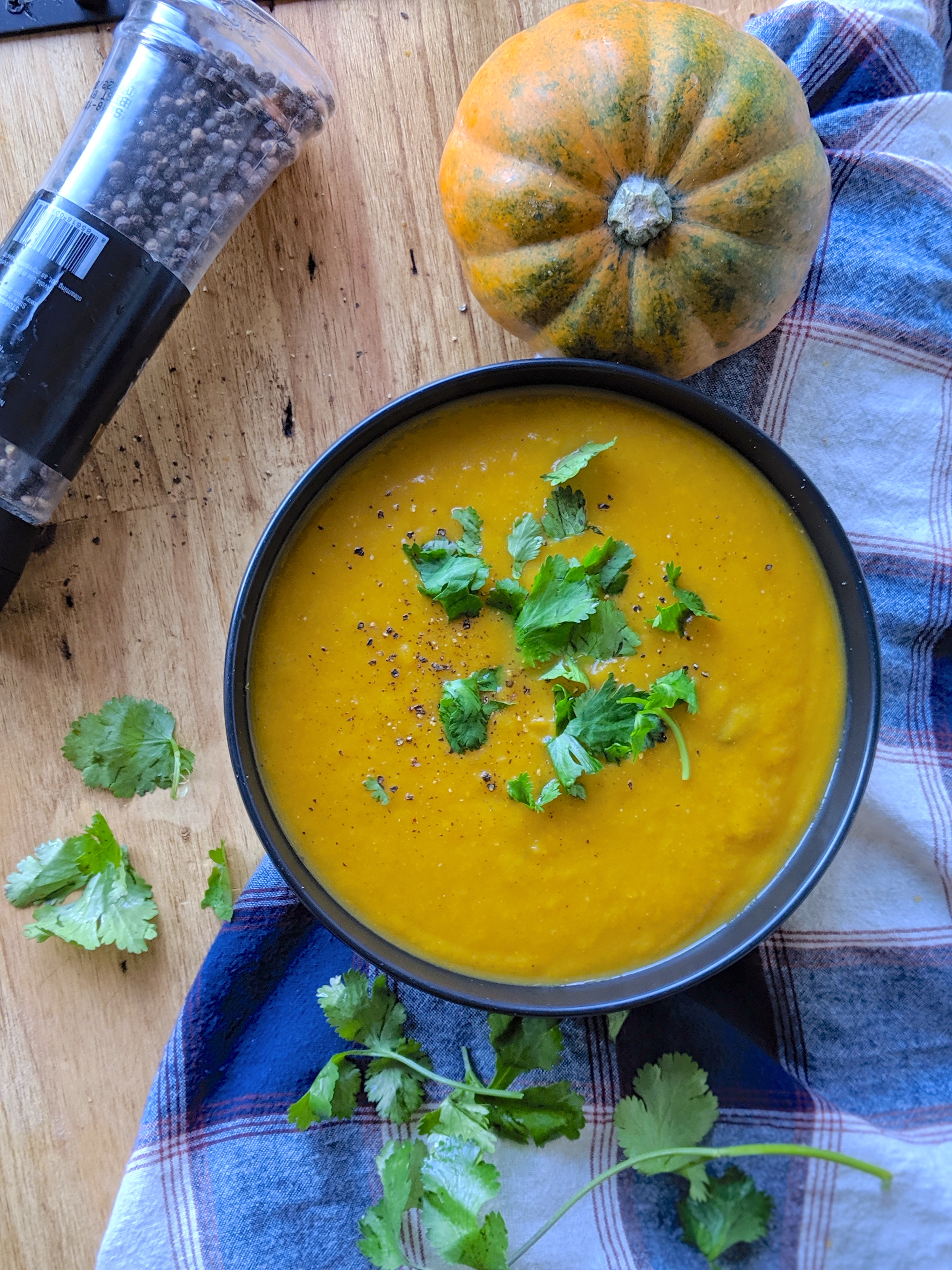 a big bowl of butternut squash apple soup with cilantro and black cracked pepper