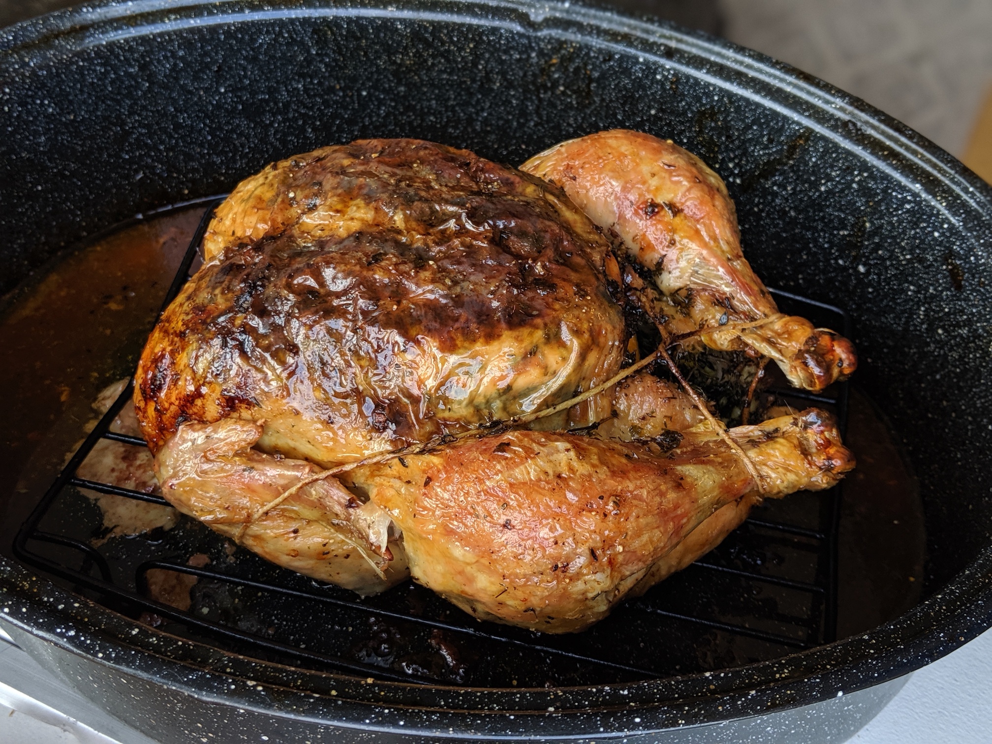a golden brown roasted chicken in a roasting pan