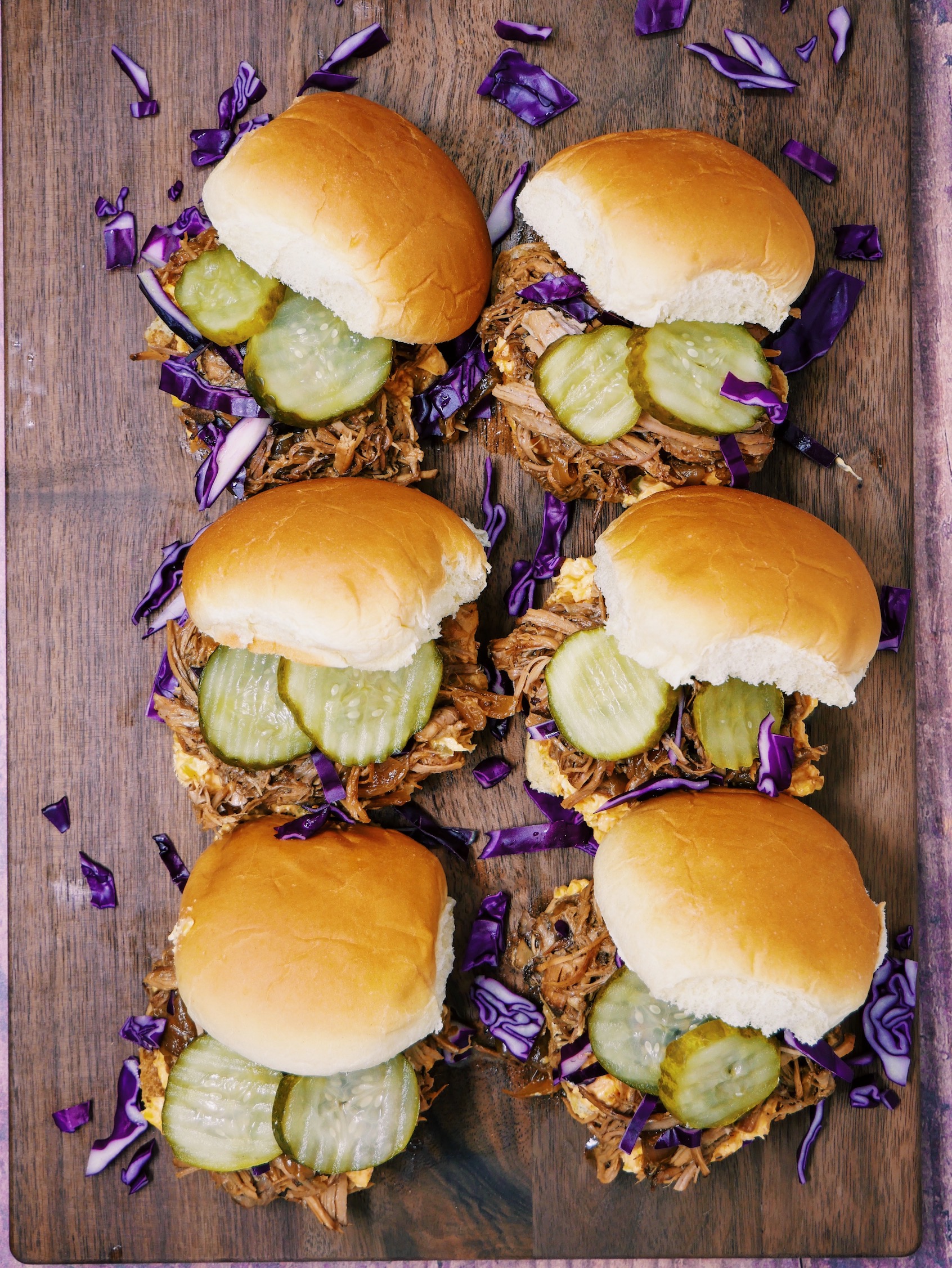 a plate of Slow Cooker Pulled Pork Sriracha Pimento Sliders with pickles and red cabbage