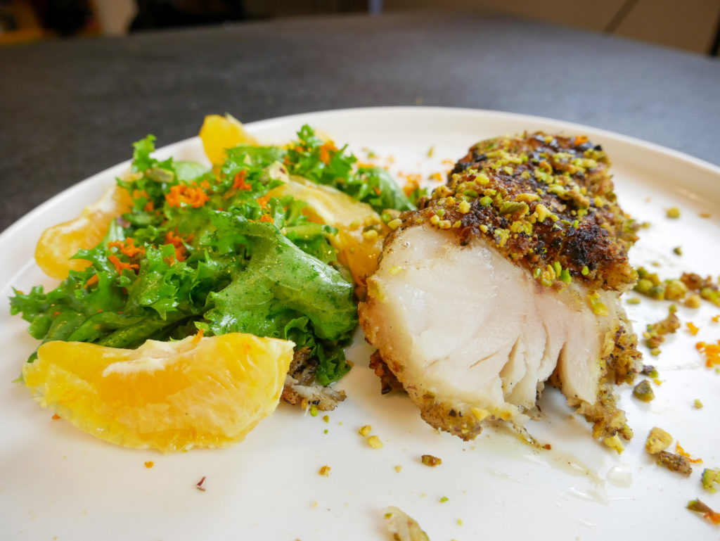a bright plate of pistachio crusted cod with an escarole salad and orange lime vinaigrette
