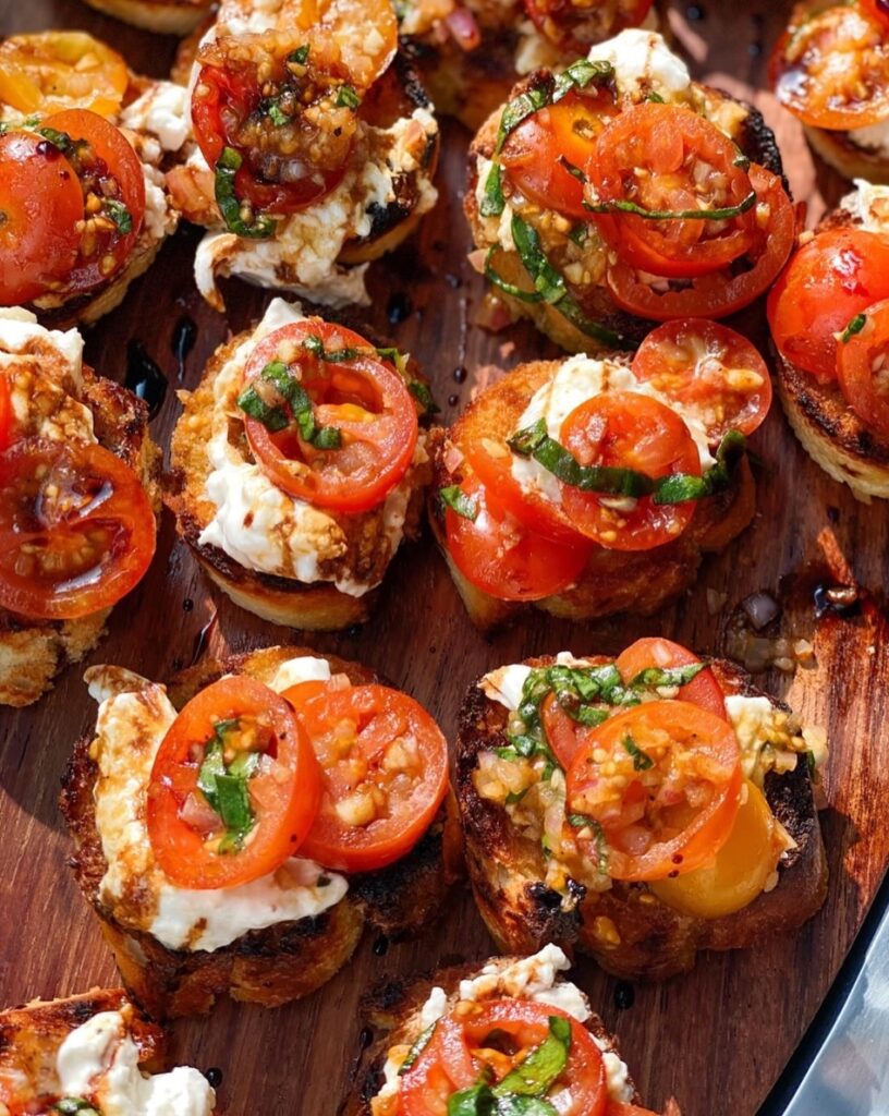 Close-up of burrata bruschetta topped with cherry tomatoes, fresh basil, and balsamic glaze on toasted baguette – easy summer appetizer for tomato season