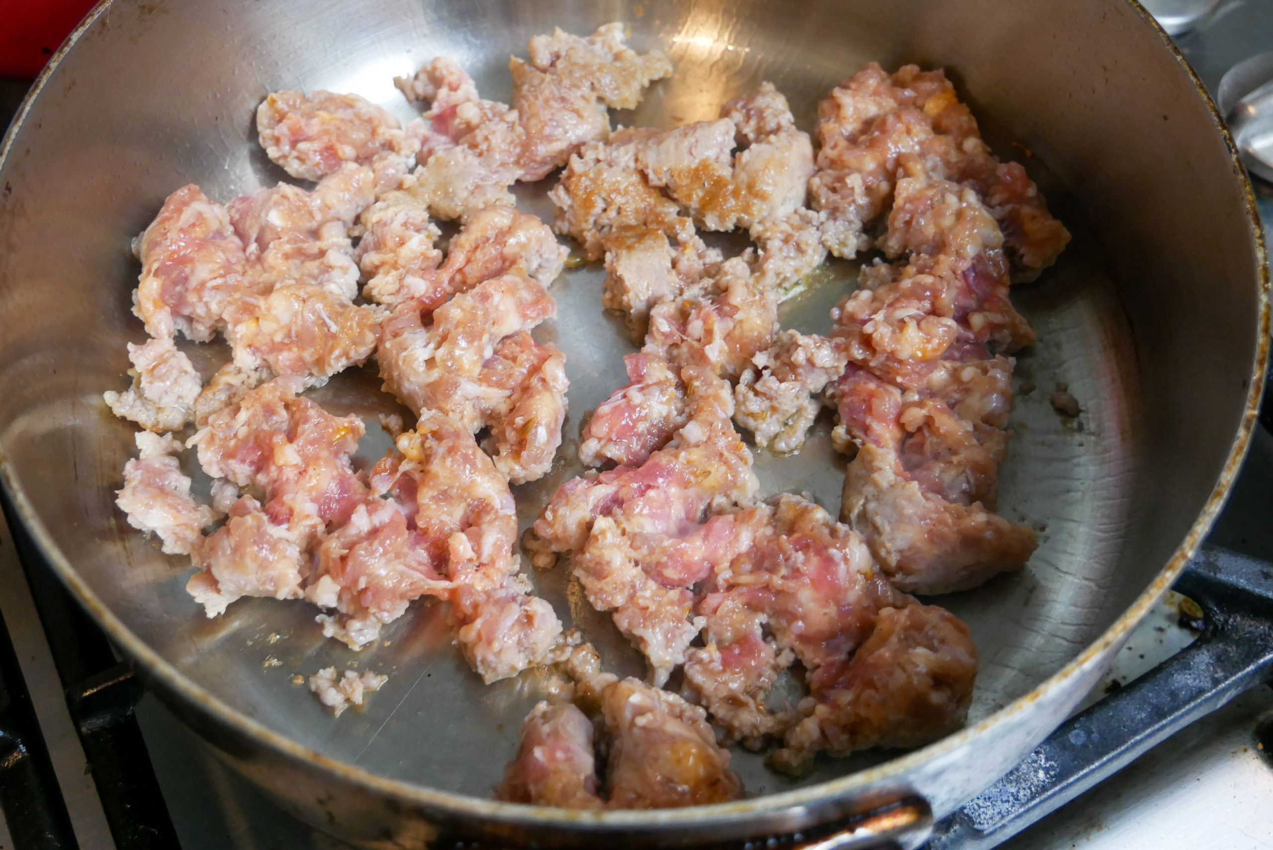 sweet Italian sausage cooking in a skillet