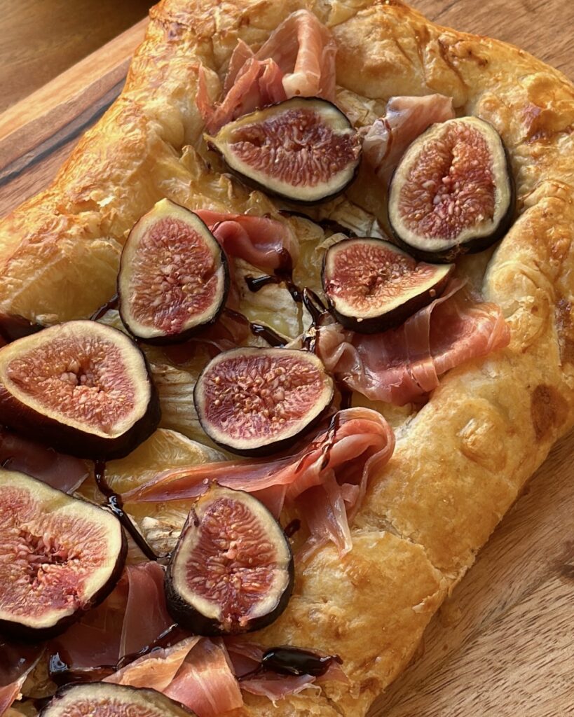 close up of sliced fig brie prosciutto galette appetizer drizzled with honey