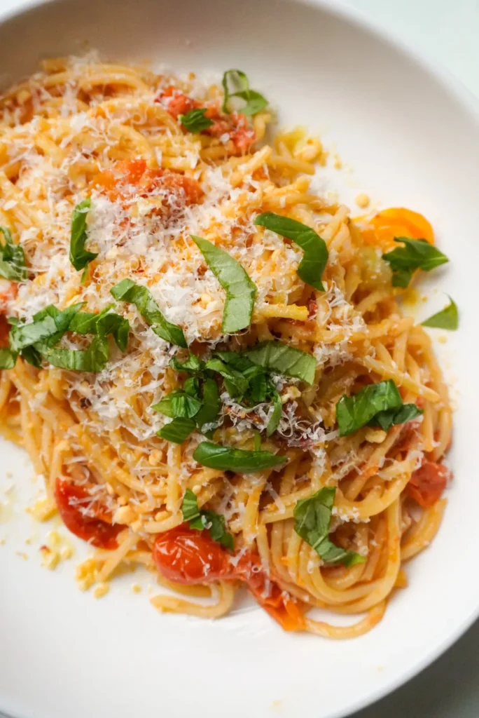 Close-up of bucatini with tomato butter sauce and crispy lemon breadcrumbs on a white plate