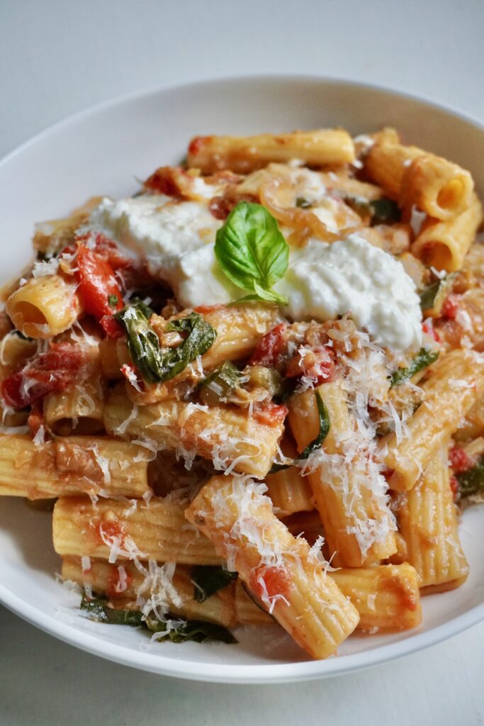 Hearty pasta dish with rigatoni tossed in a rich caramelized ratatouille sauce of zucchini, eggplant, peppers, and tomatoes, served with fresh cheese and herbs