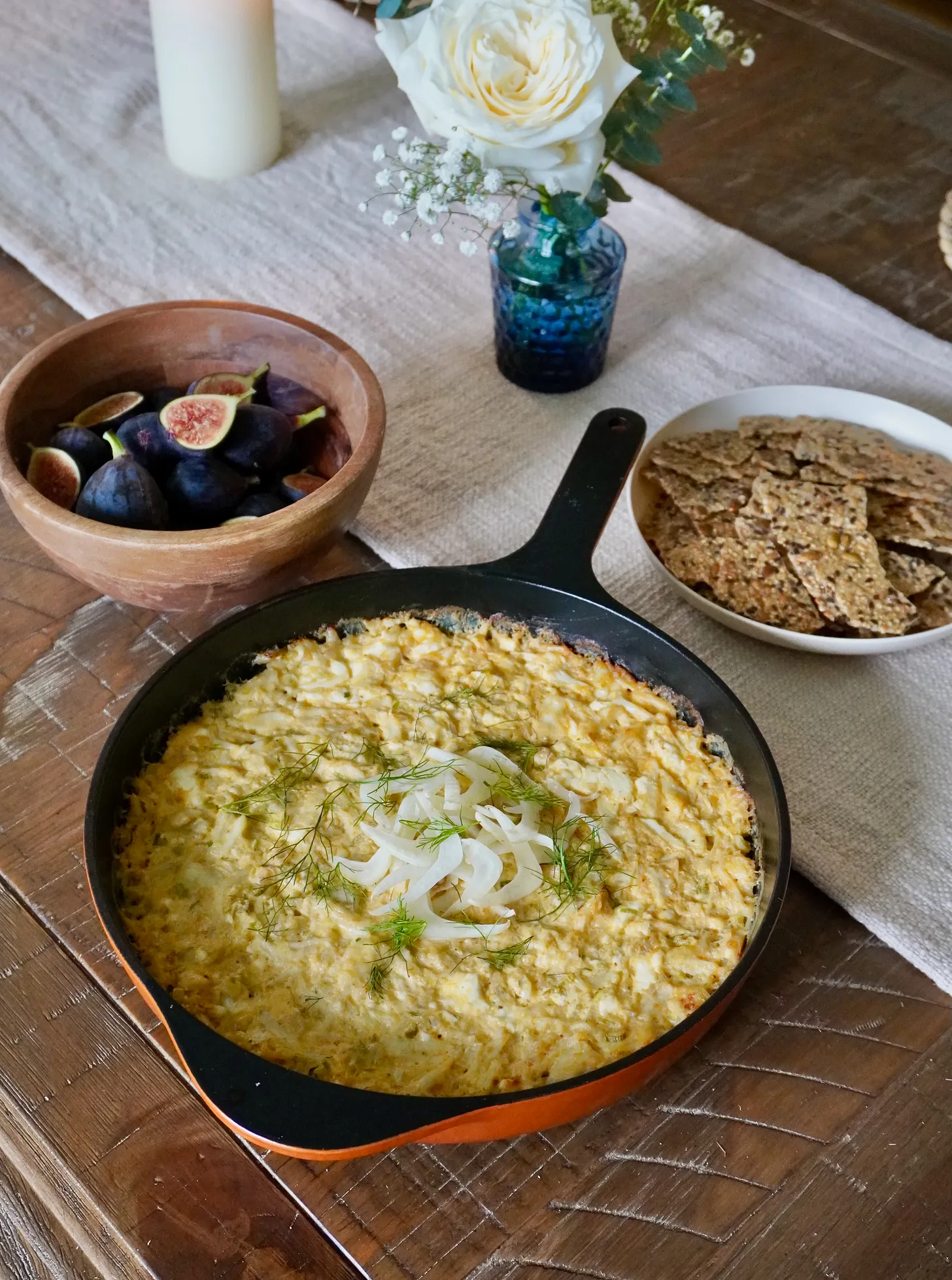 Creamy crab dip in a skillet topped with herbs and served with seeded crackers for a September dinner menu