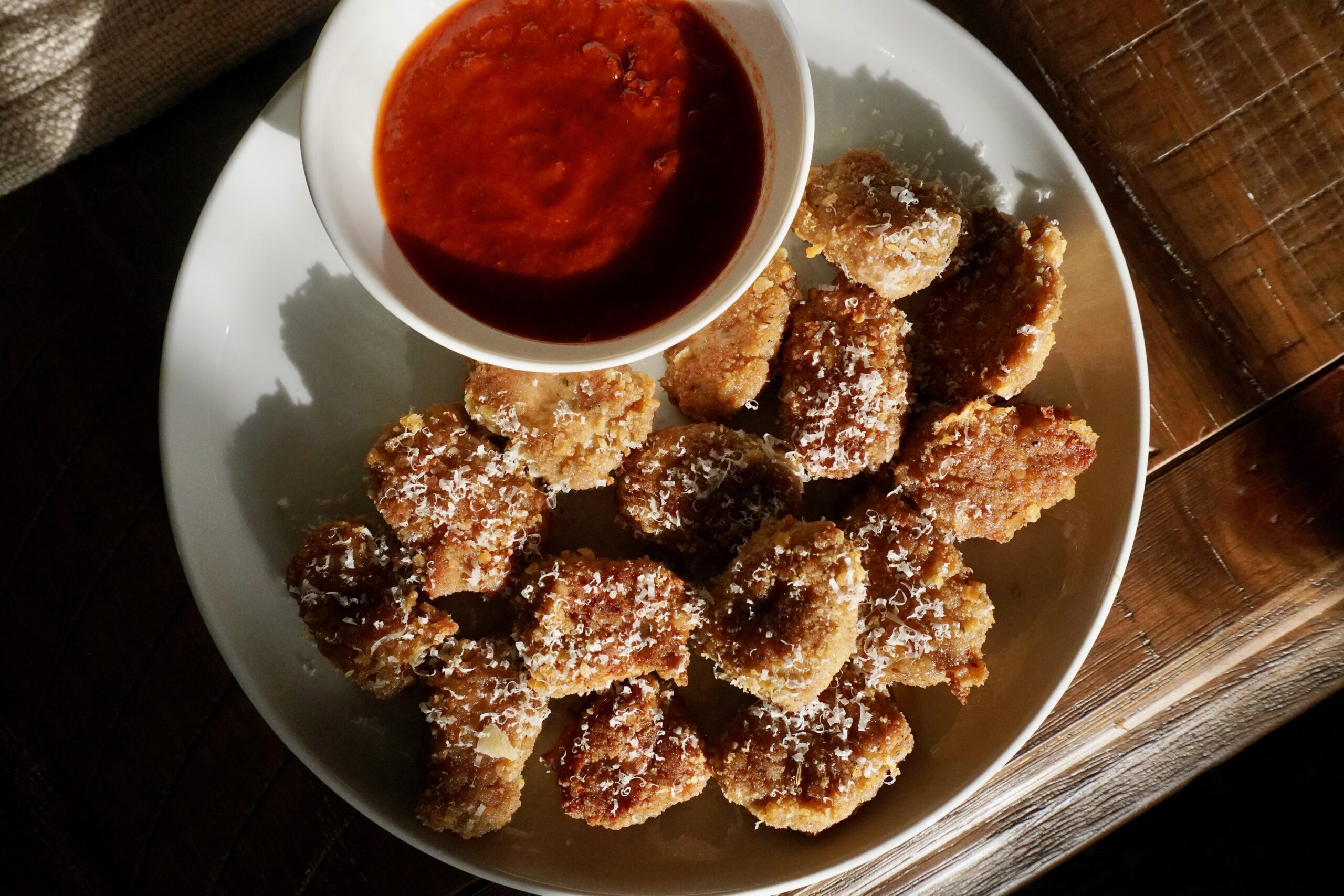 Family-style platter of garlic parmesan turkey nuggets with marinara sauce in the center for dipping.