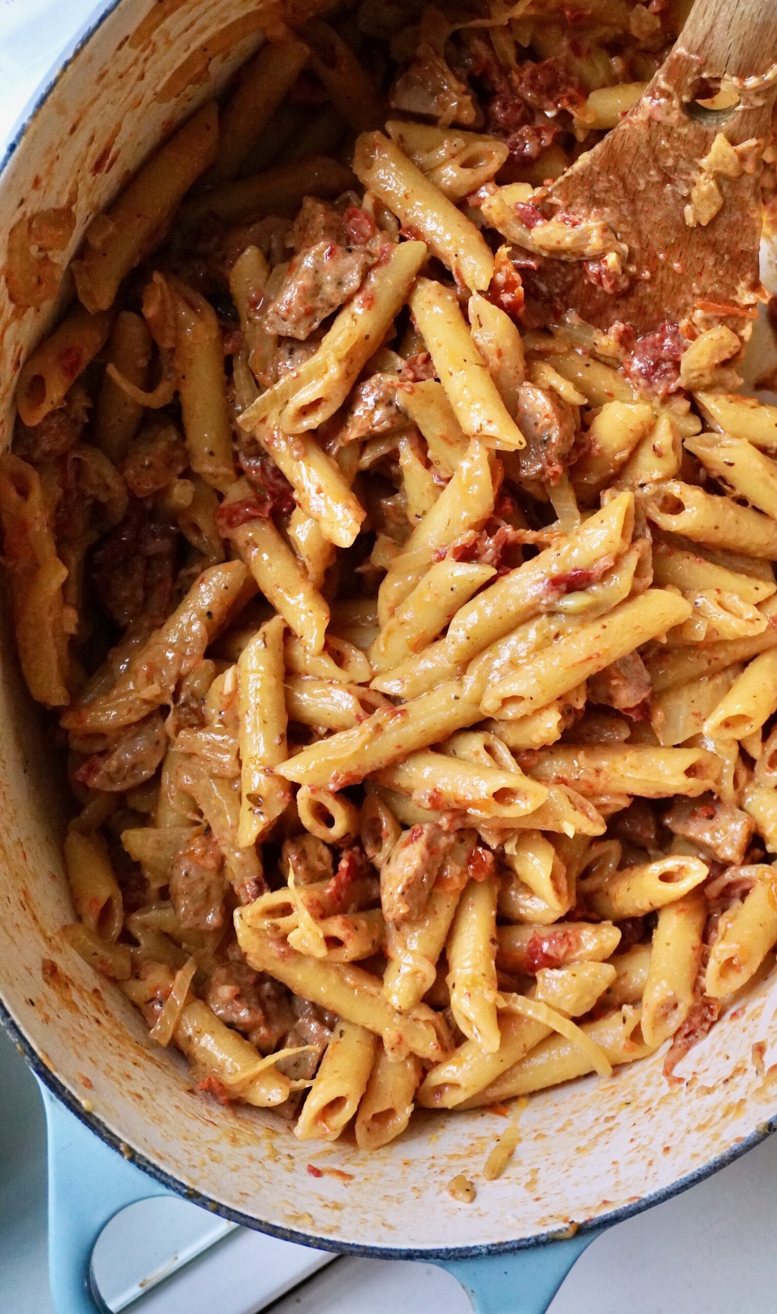 Overhead shot of one-pot chicken sausage fennel and sun-dried tomato penne in a Dutch oven with creamy Parmesan sauce