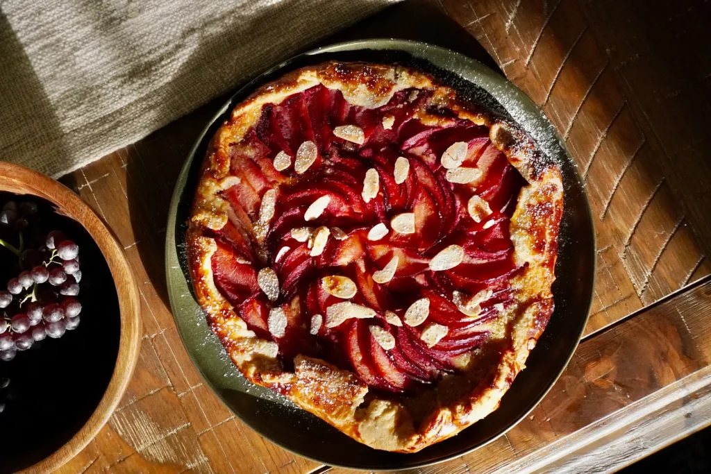 Rustic galette with sliced plums and golden almond filling on flaky pastry for a September dinner menu