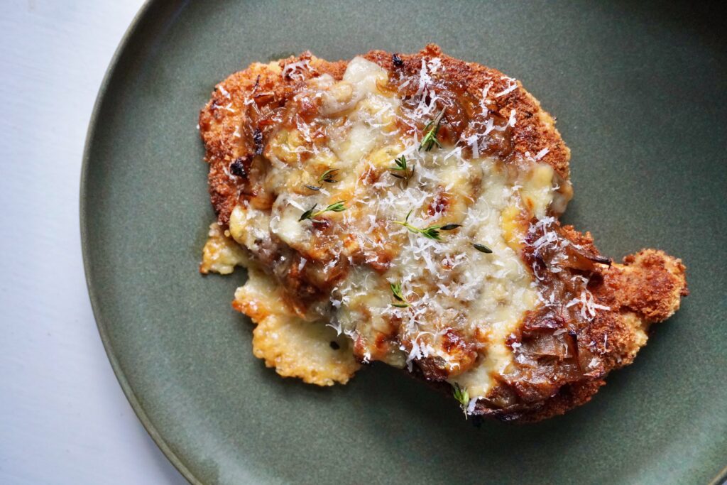 Close-up of cheesy French onion chicken with thyme garnish