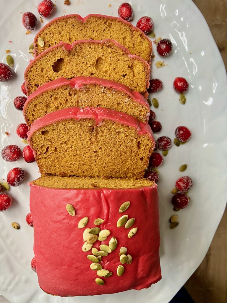 Overhead shot of pumpkin loaf with glossy pink-red glaze.