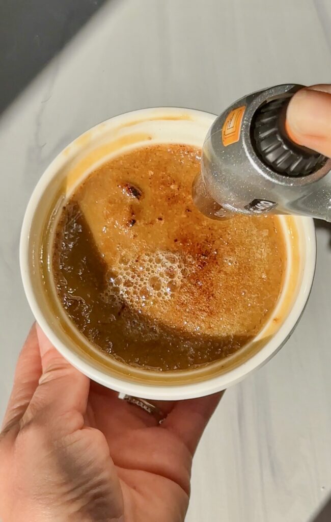 Chai crème brûlée with caramelized sugar crust and steam rising from the custard.