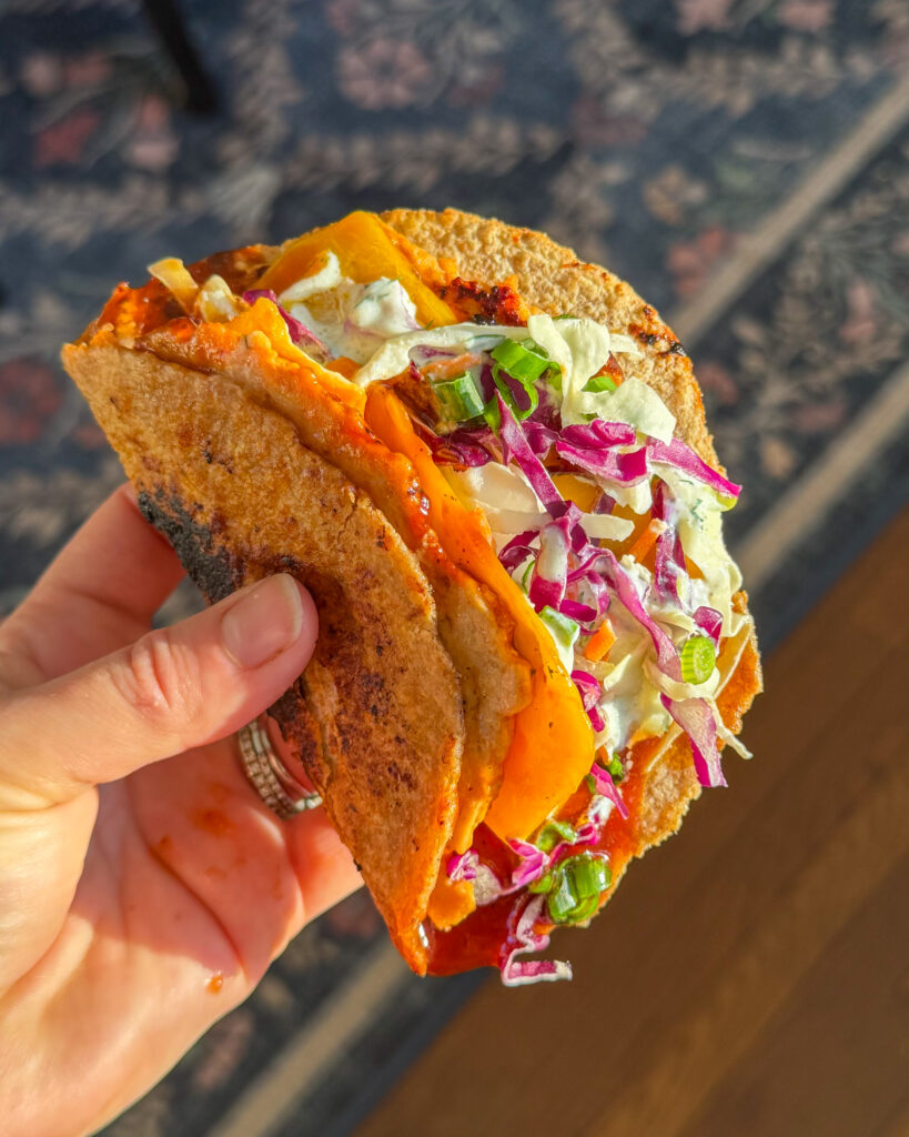 a close up image of BBQ chicken tacos filled with smoky chicken tangy slaw and ranch