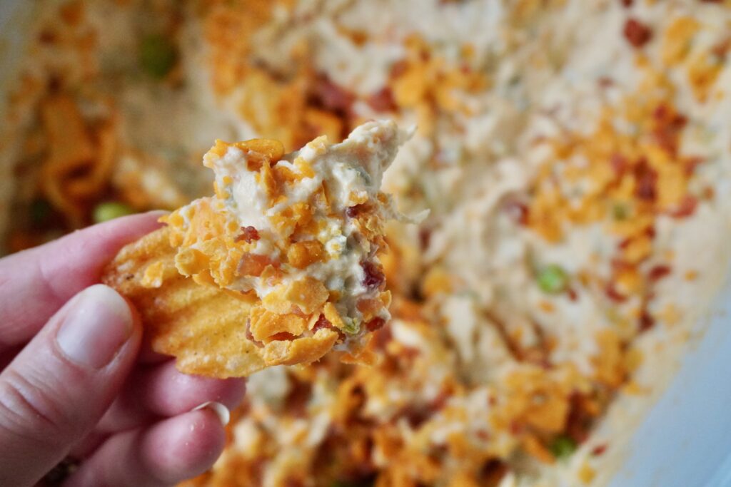 a bbq crinkle chip dipped into jalapeno popper chicken dip int eh crockpot