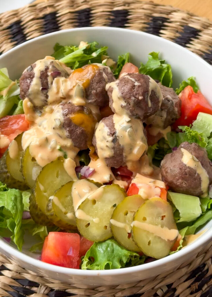 Close up of a cheese-stuffed meatball cut open to show melted cheddar center in a Big Mac bowl