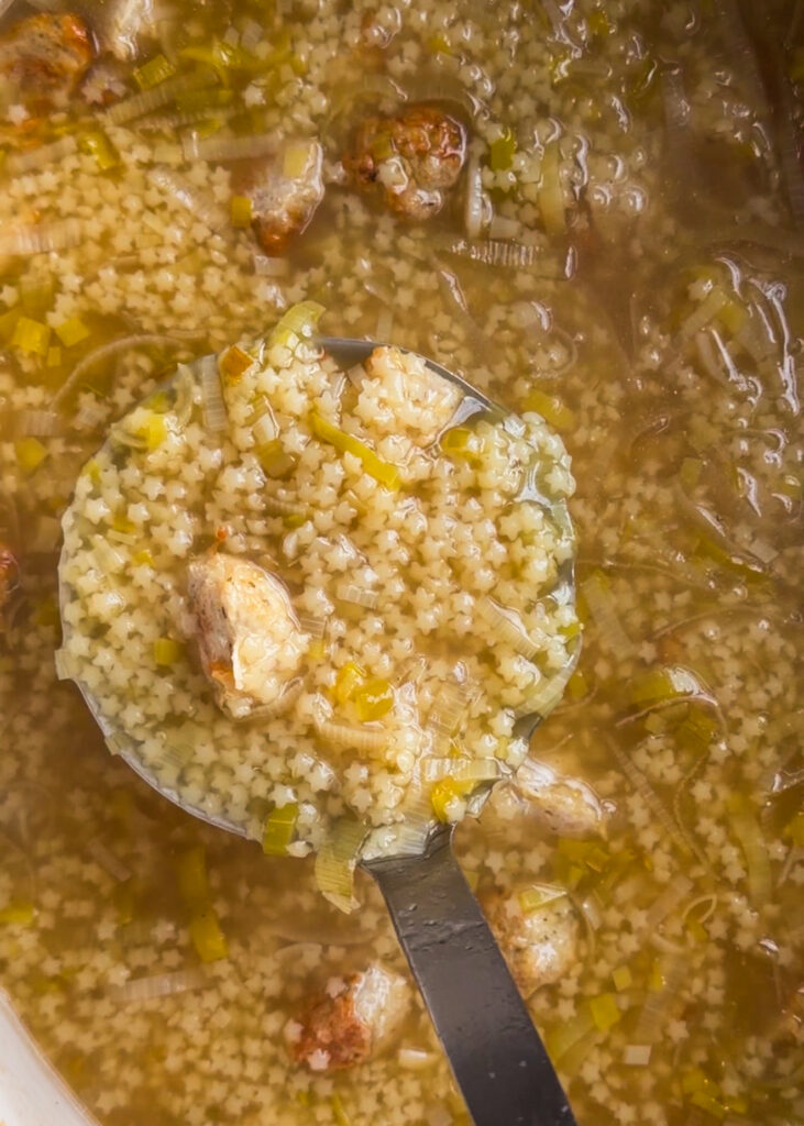 A cozy bowl of lemony leek pastina soup topped with mini roasted chicken meatballs and freshly grated parmesan cheese