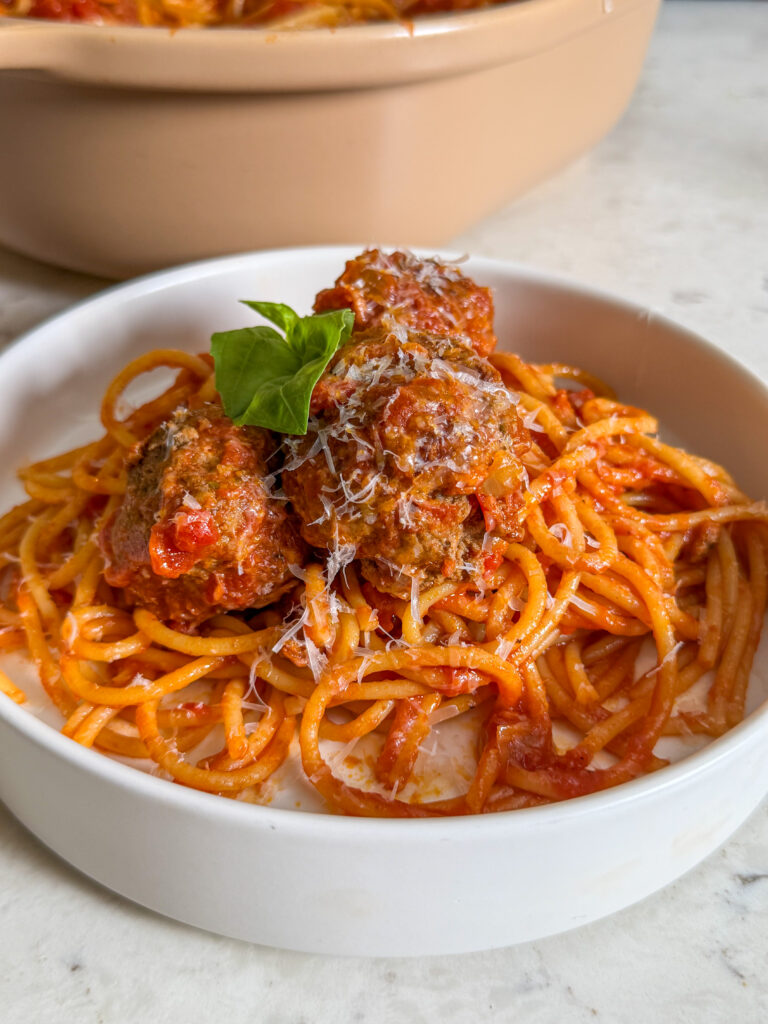 A bowl of spaghetti tossed in marinara sauce, topped with tender slow cooker Italian meatballs, fresh basil, and grated parmesan
