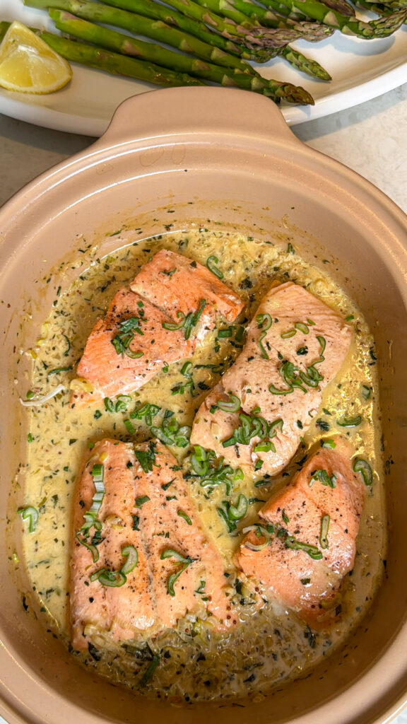 Salmon skin-side down sizzling in a cast-iron braiser