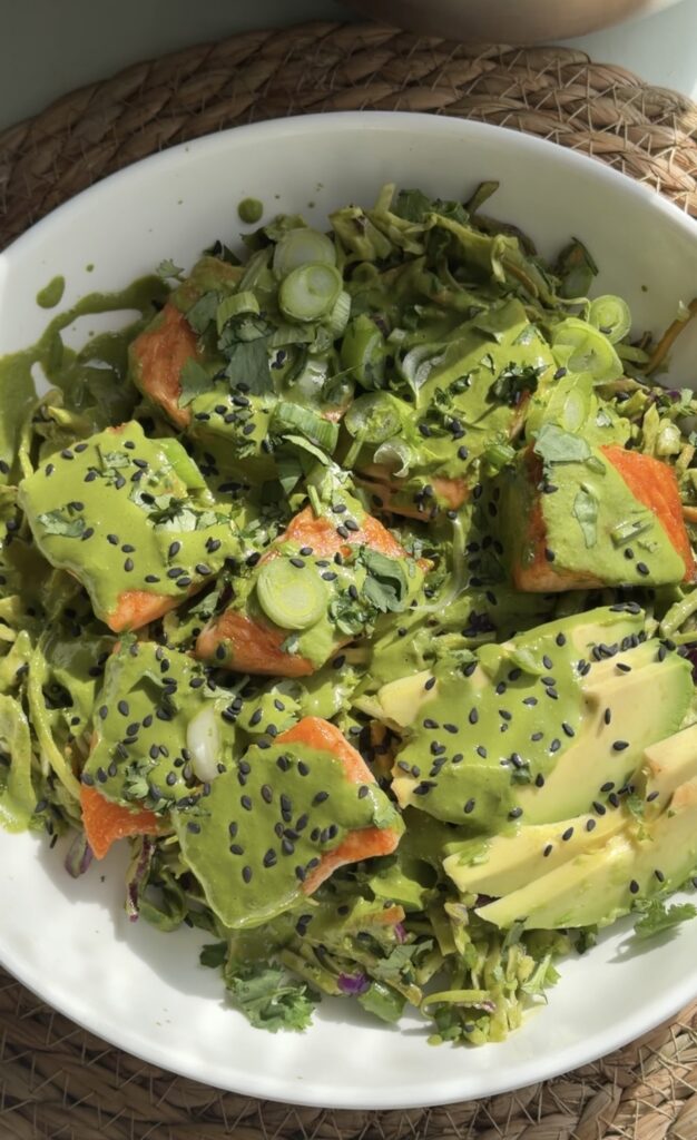 Healthy salmon rice bowl with cabbage slaw mix drizzled with green goddess dressing over a bed of fluffy rice