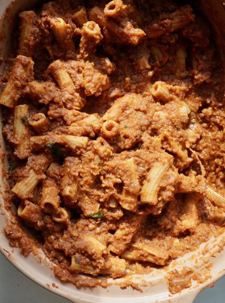 A slow cooker filled with simmering tomatoes, eggplant, and green lentils