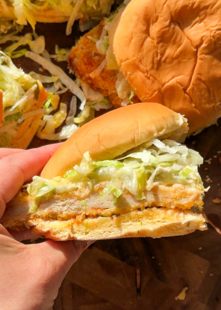 Close-up of spicy dill pickle chicken sliders with creamy sauce dripping