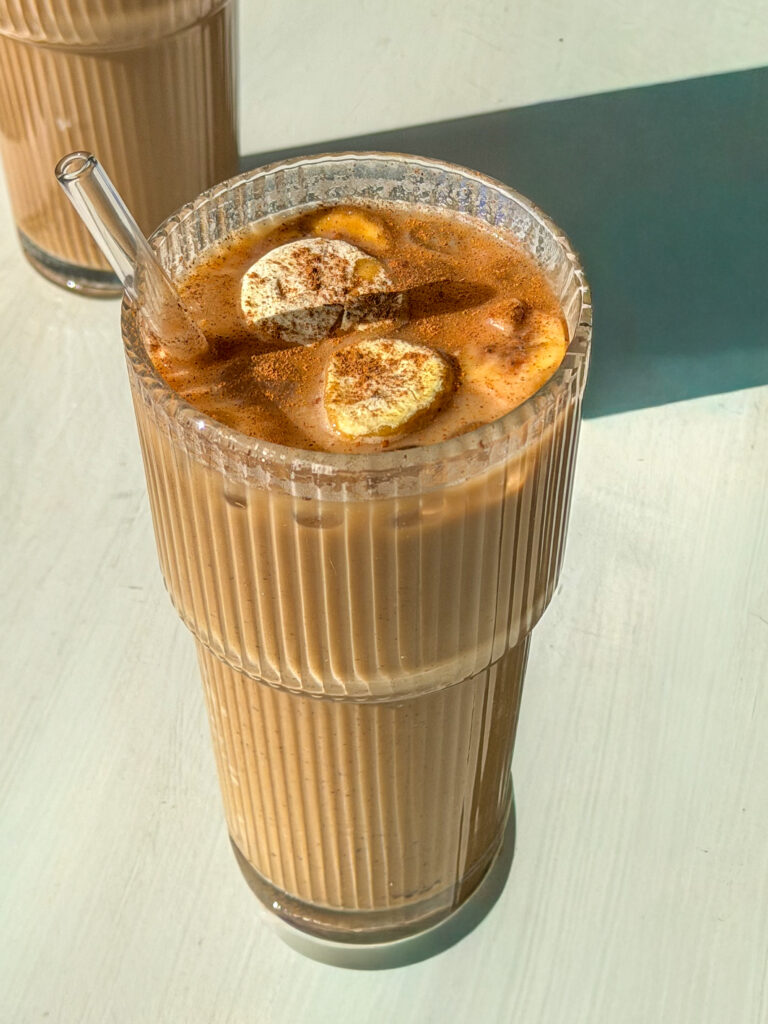 Iced banana bread latte in a glass with creamy milk and dusted with cinnamon on top