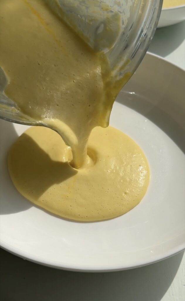 Silky corn purée swirled from a blender on a plate with a glossy finish
