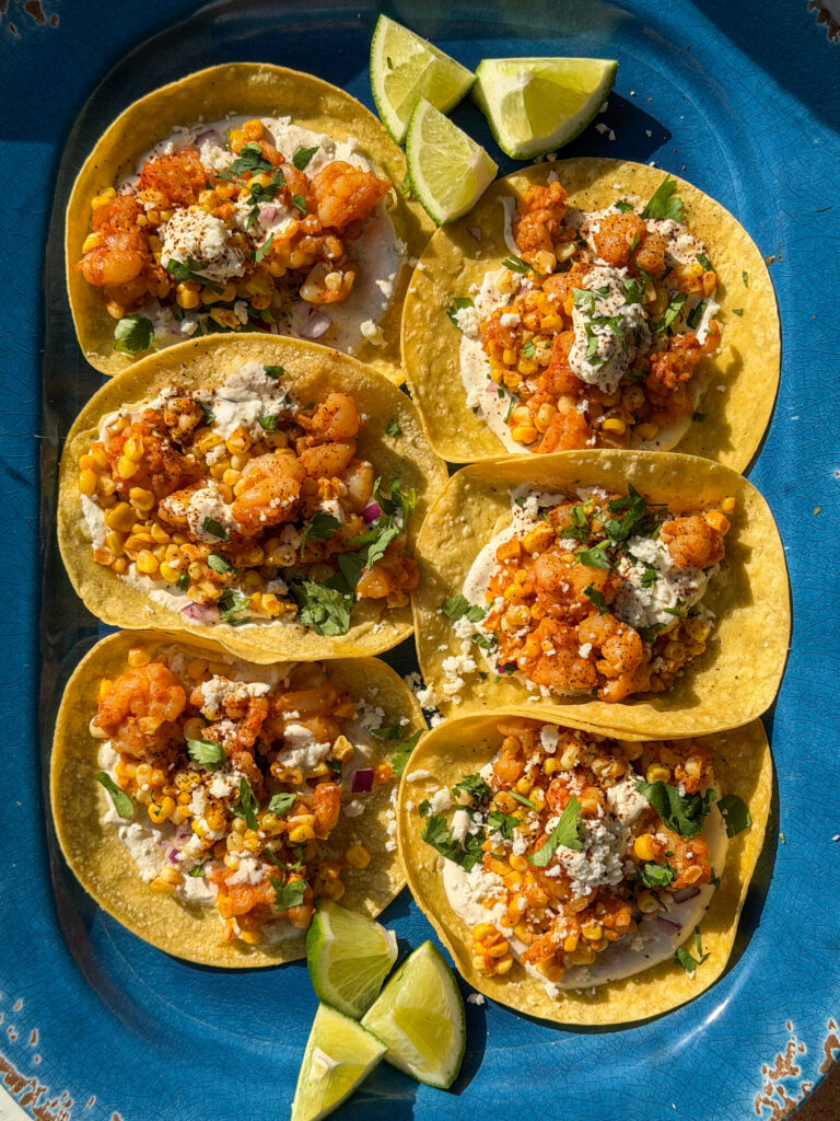 Close-up of Chipotle shrimp tacos with charred corn filling, lime crema, and cotija cheese