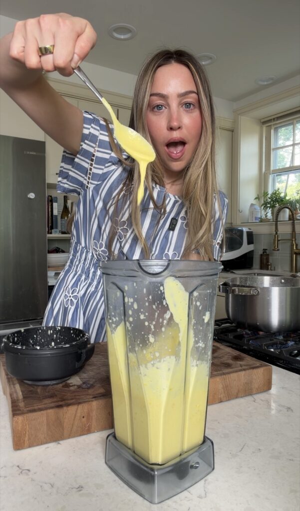 Creamy corn purée is being swirled with a spoon from a blender 