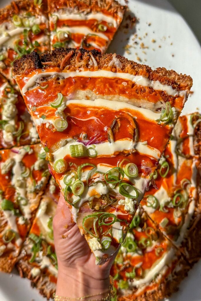 hand holding a slice of chicken pizza