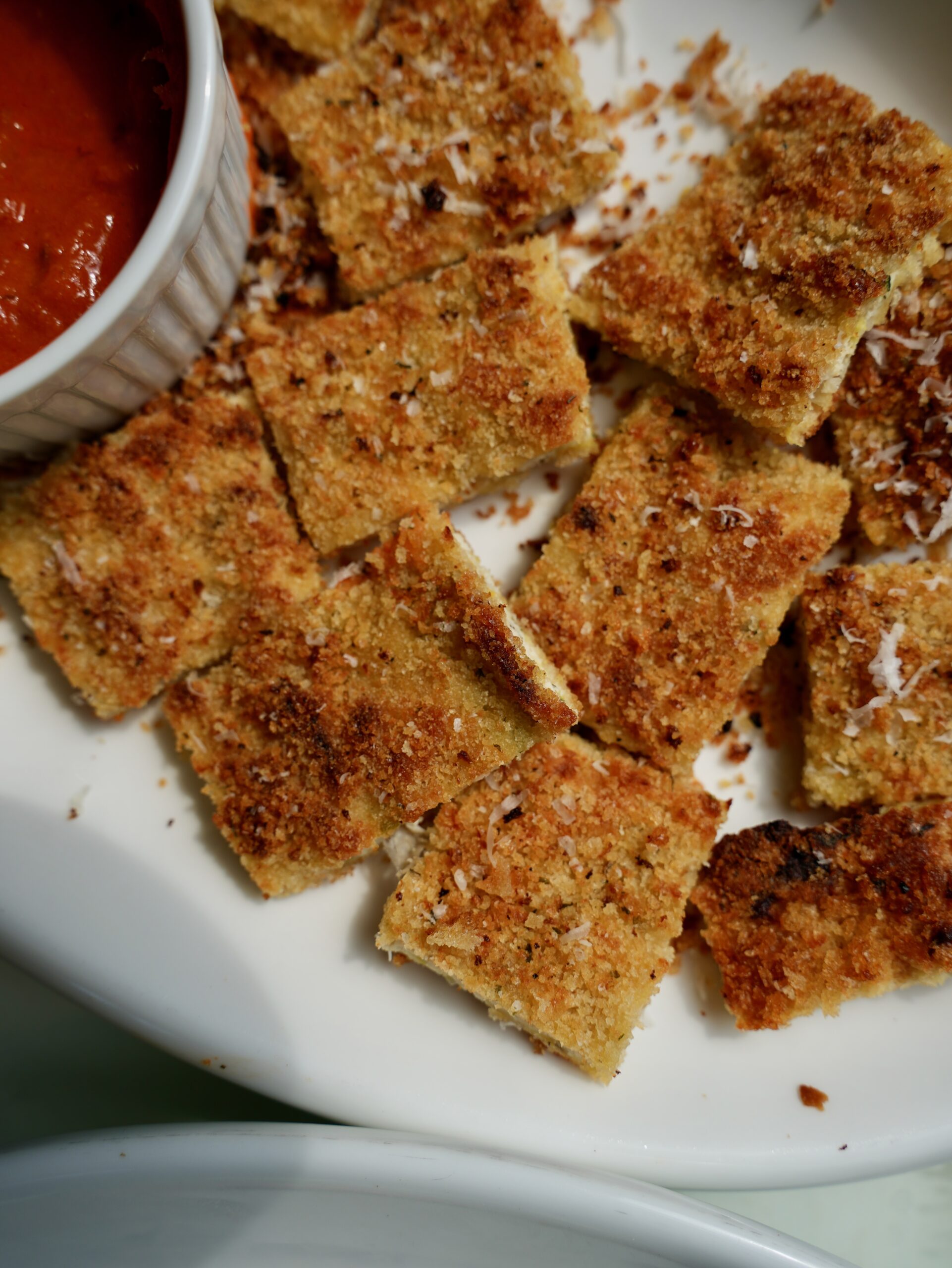 Crispy baked zucchini Parmesan chicken cutlet sliced into squares with marinara sauce