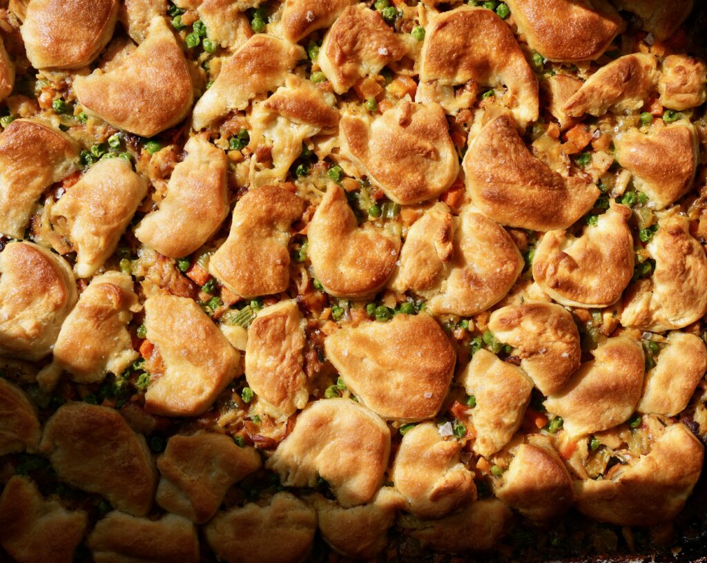 Trader Joe’s sheet pan chicken pot pie topped with golden torn biscuits, peas and fall vegetables